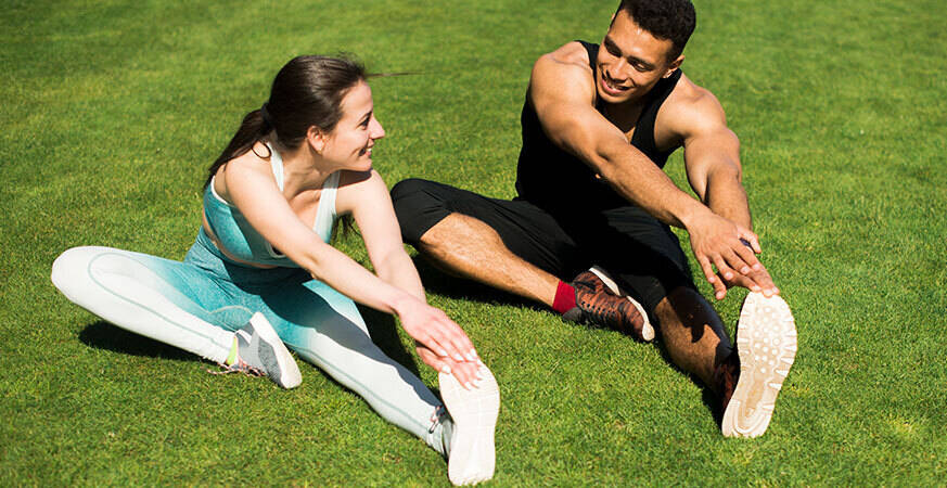 man and woman stretching their legs outdoors