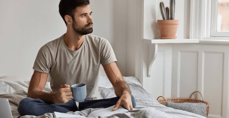 man sitting on bed looking thoughtful