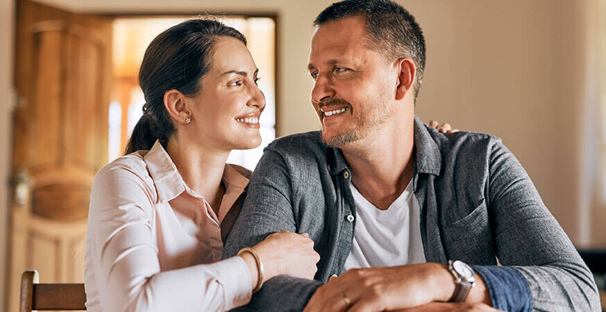 Smiling couple sitting together indoors.