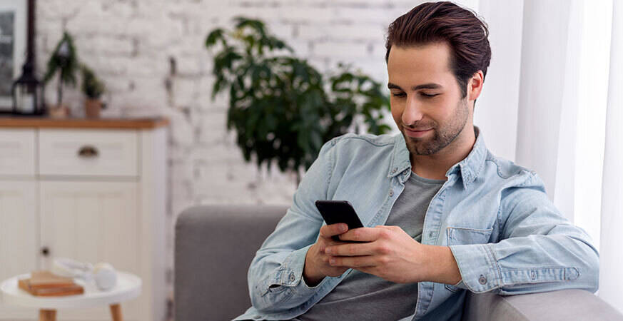 man holding a phone sitting on a sofa