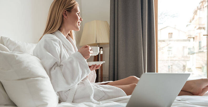 woman holding a cup and sitting on a bed