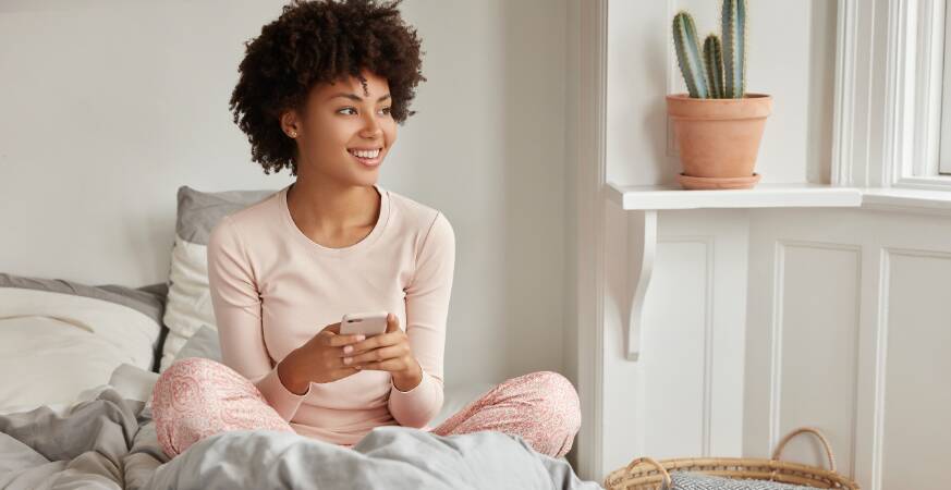 woman holding a cup and sitting on a bed