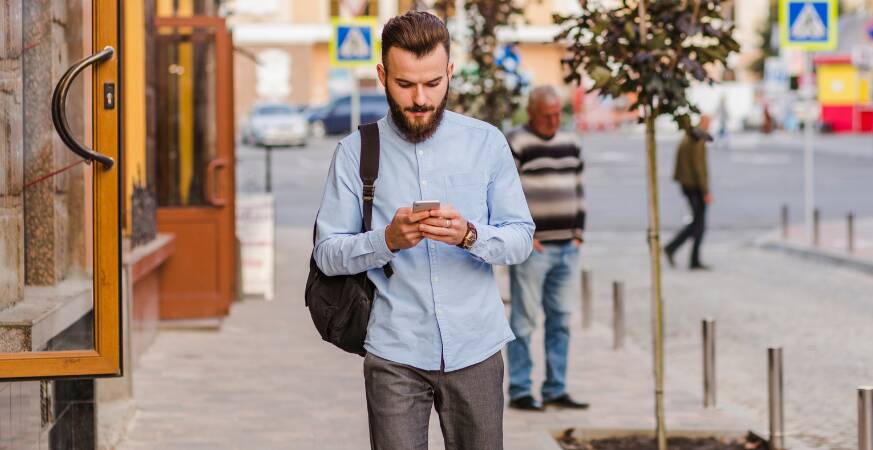 guy looking at his phone while walking