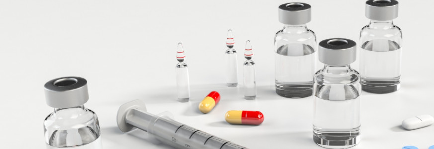 Medical supplies, ampoules, syringe, and assorted pills on a white table